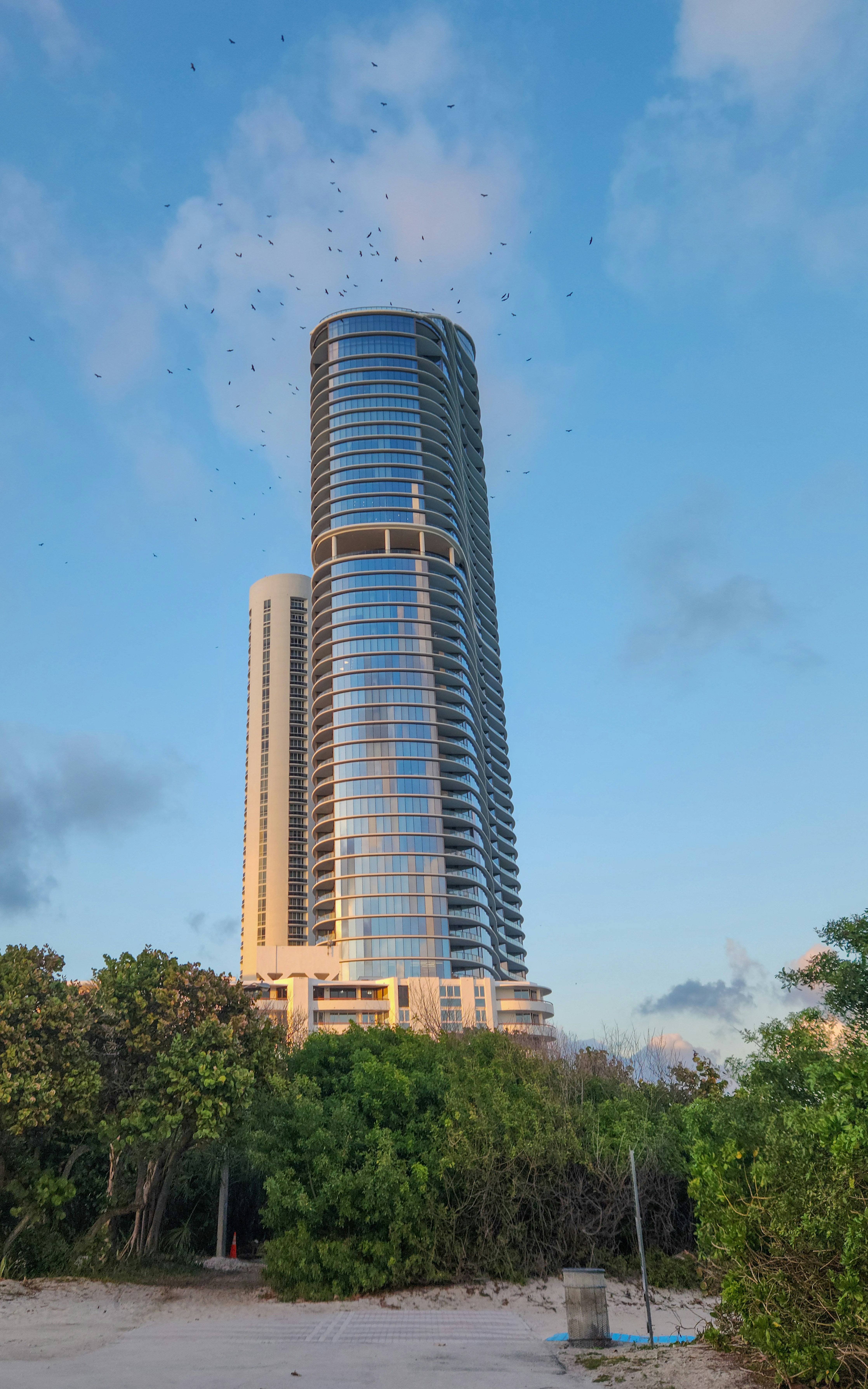 A very tall building with a lot of birds flying around it