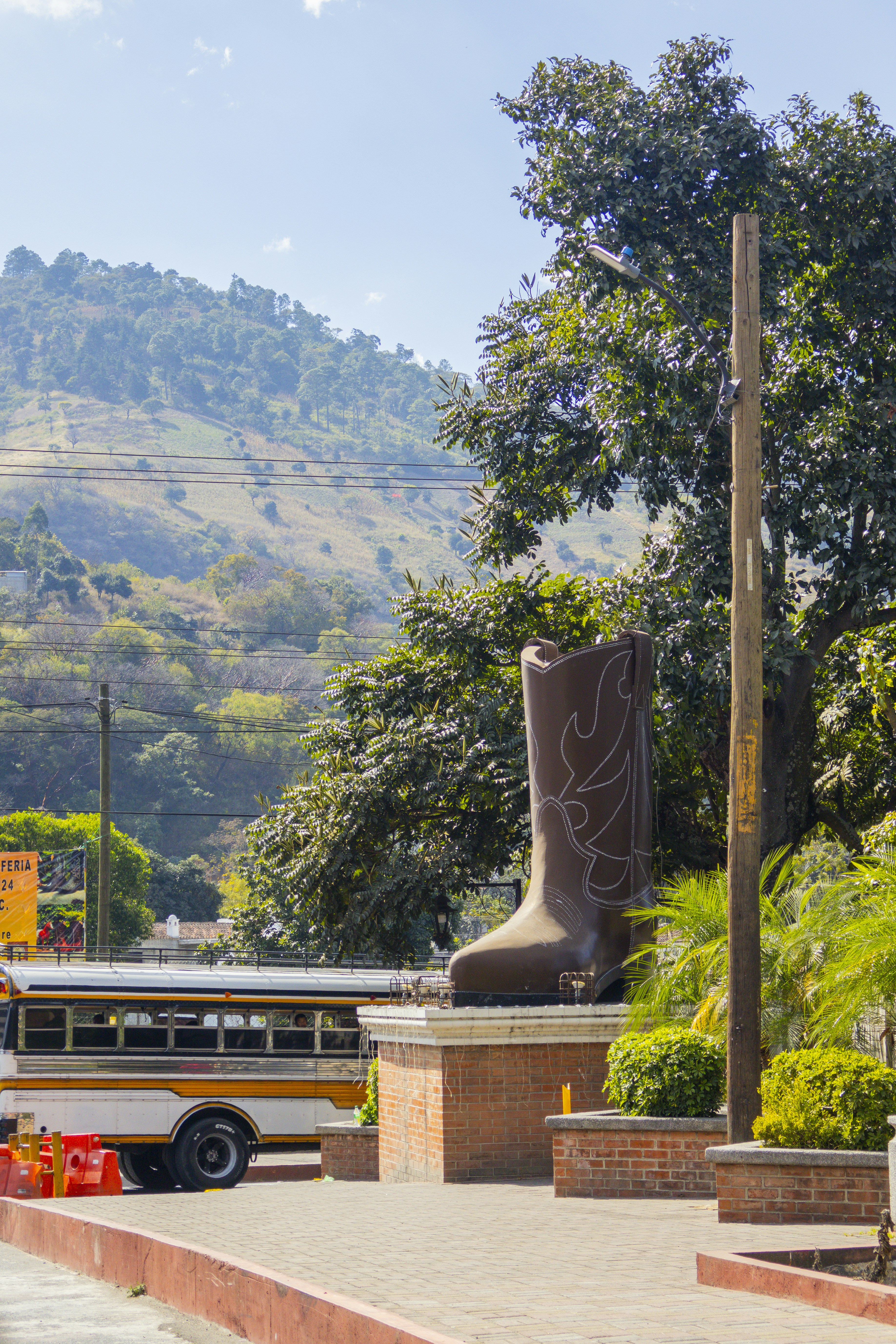 A bus is parked in front of a statue of a boot