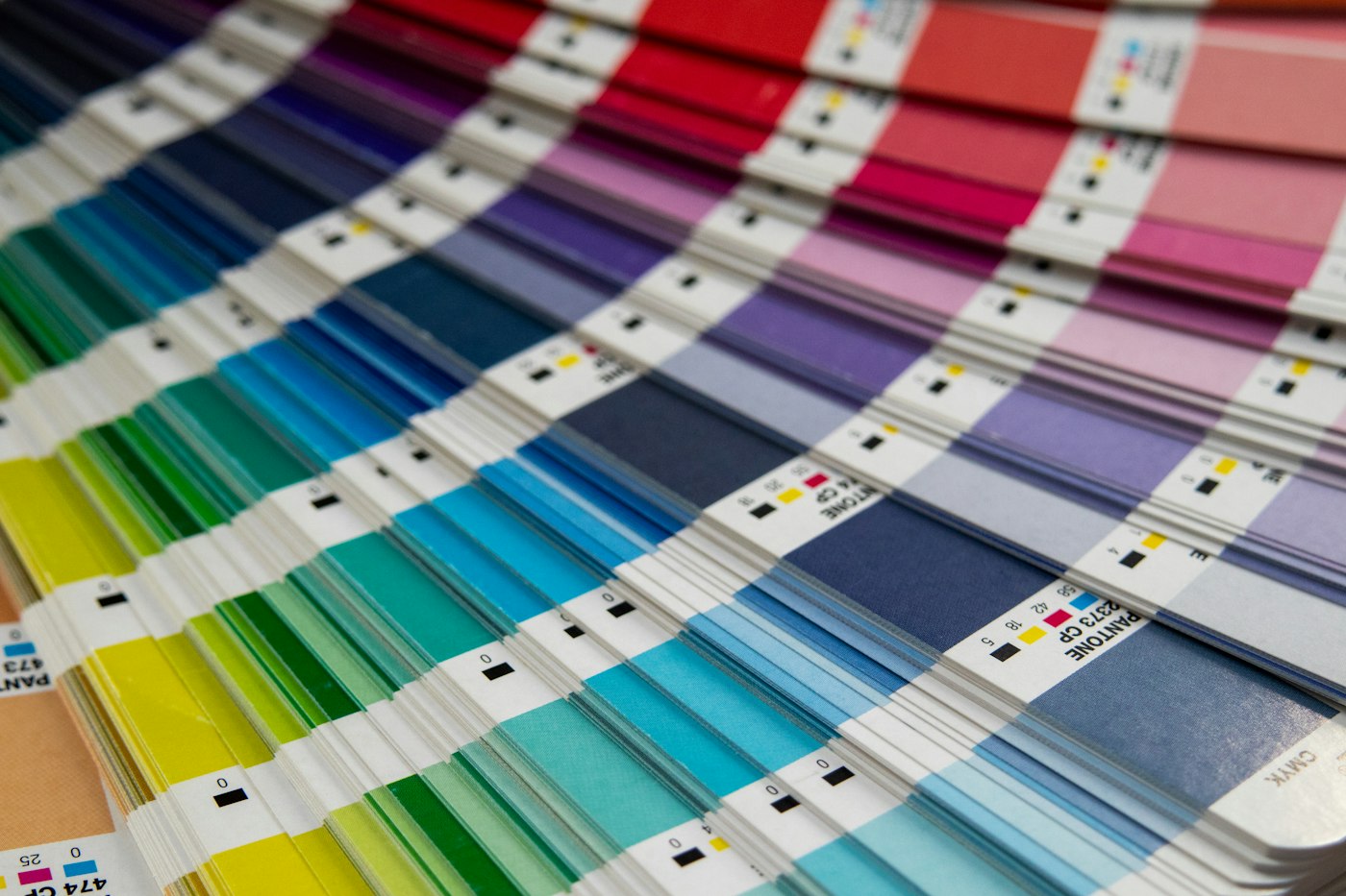 Printed Pantone color swatch decks fanned across a table, including blue, purple, and pink samples