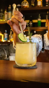 A man is holding a cocktail in a glass