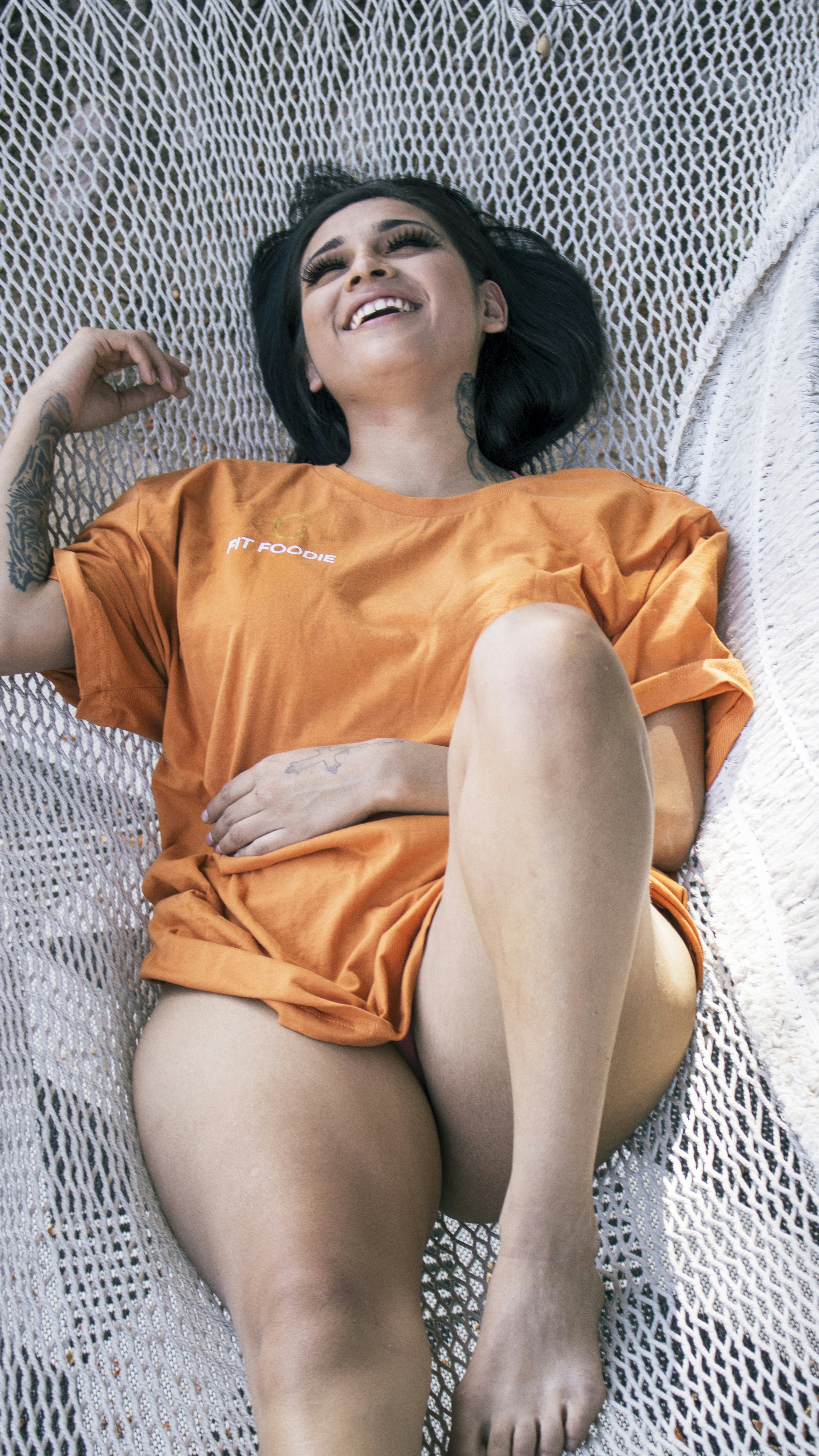 A woman in an orange shirt laying on a hammock