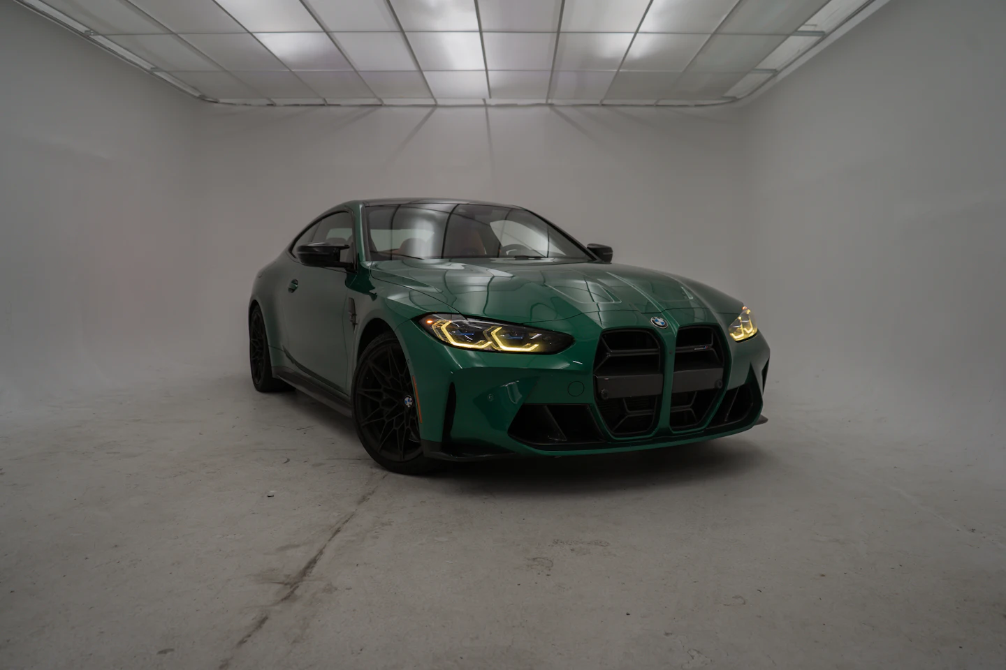 Green performance car with a mirror finish in a bright white detailing studio