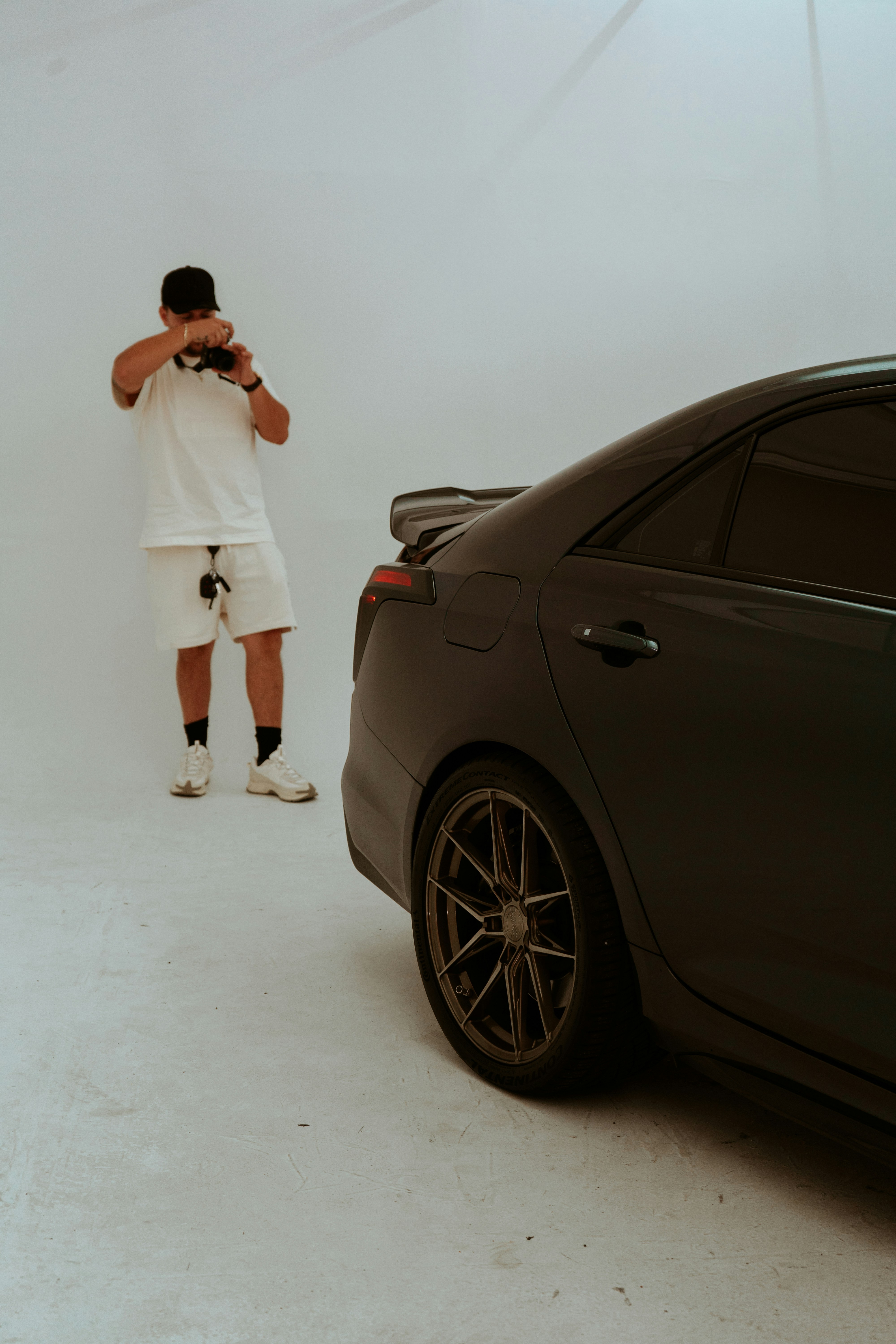 Photographer shooting a black sports car in a studio