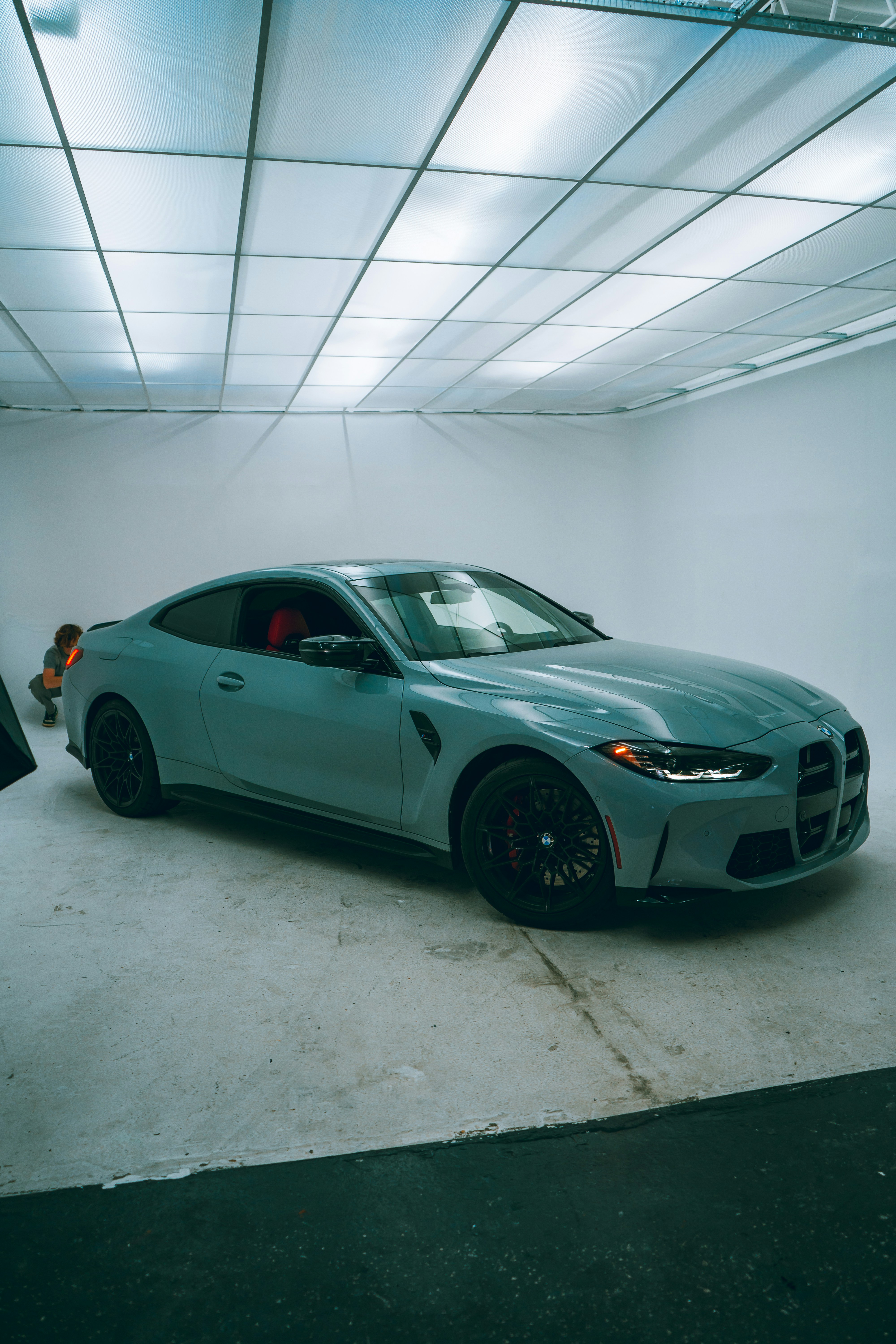A modern grey sports car is parked in a studio.