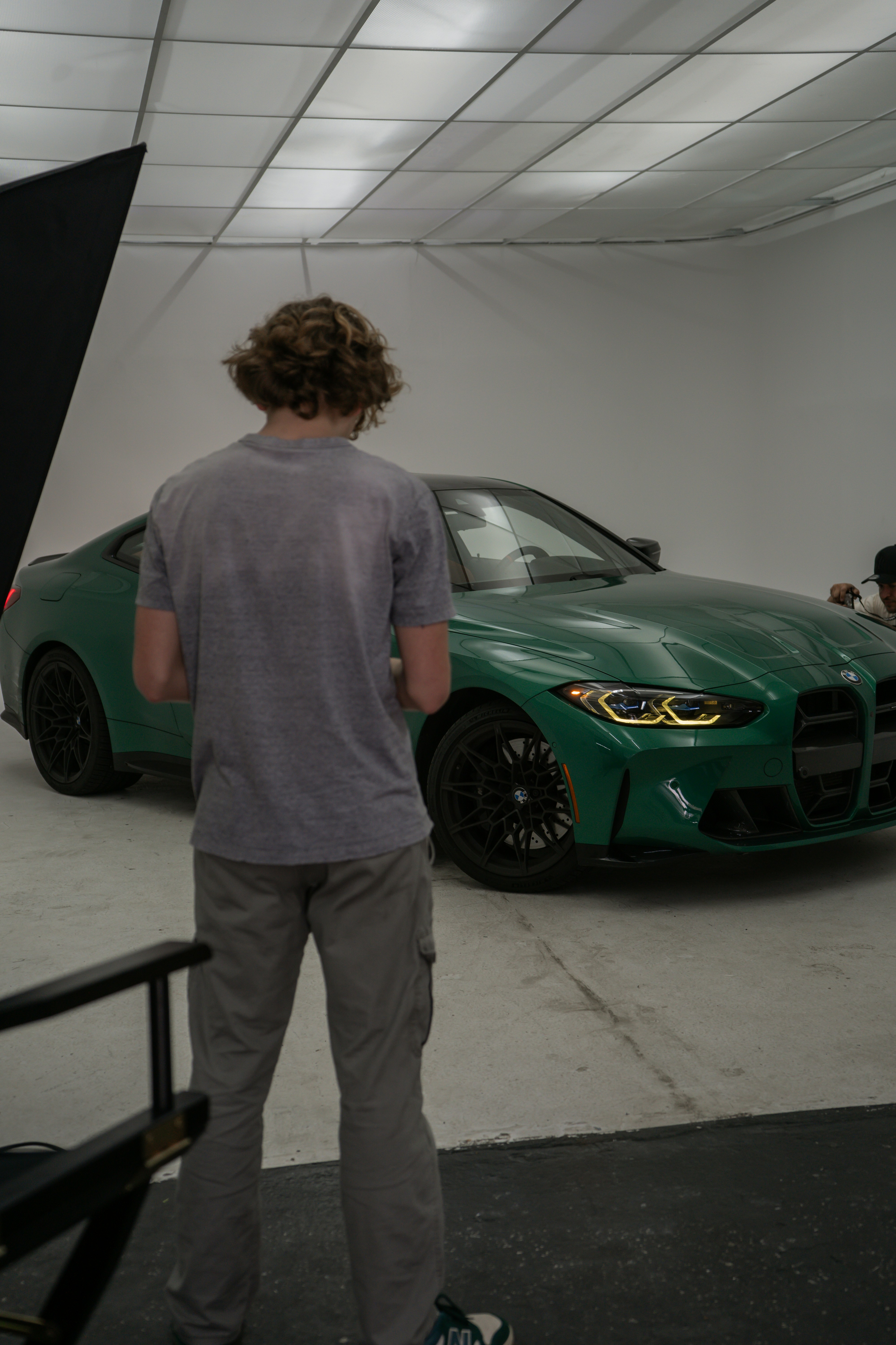 A person admires a sleek green sports car in a studio.