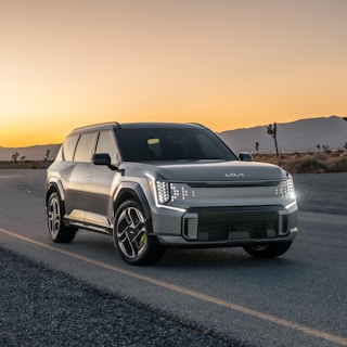 A silver suv driving down a road at sunset