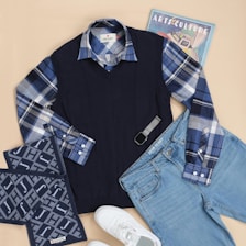 A pair of jeans, a sweater, and a pair of sneakers are laid out