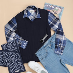 A pair of jeans, a sweater, and a pair of sneakers are laid out