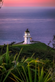 A lighthouse on a hill overlooking the ocean