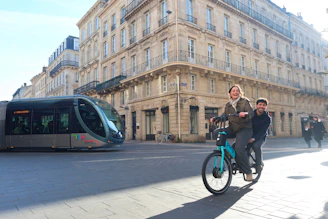 A couple of people riding a bike down a street