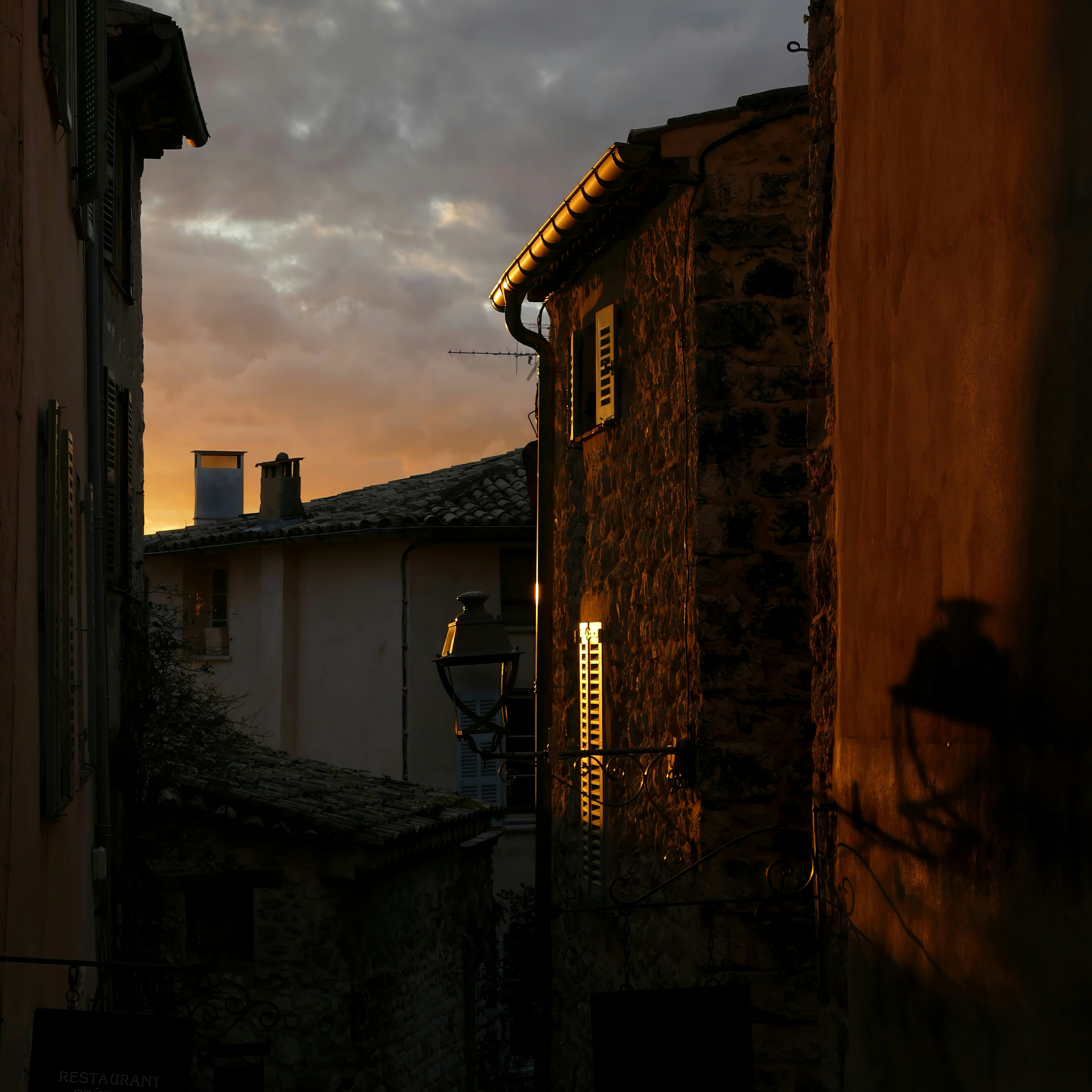 A dark alley way with a clock tower in the distance
