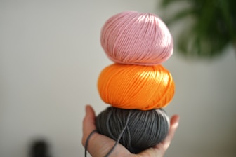 A person holding three balls of yarn in their hands