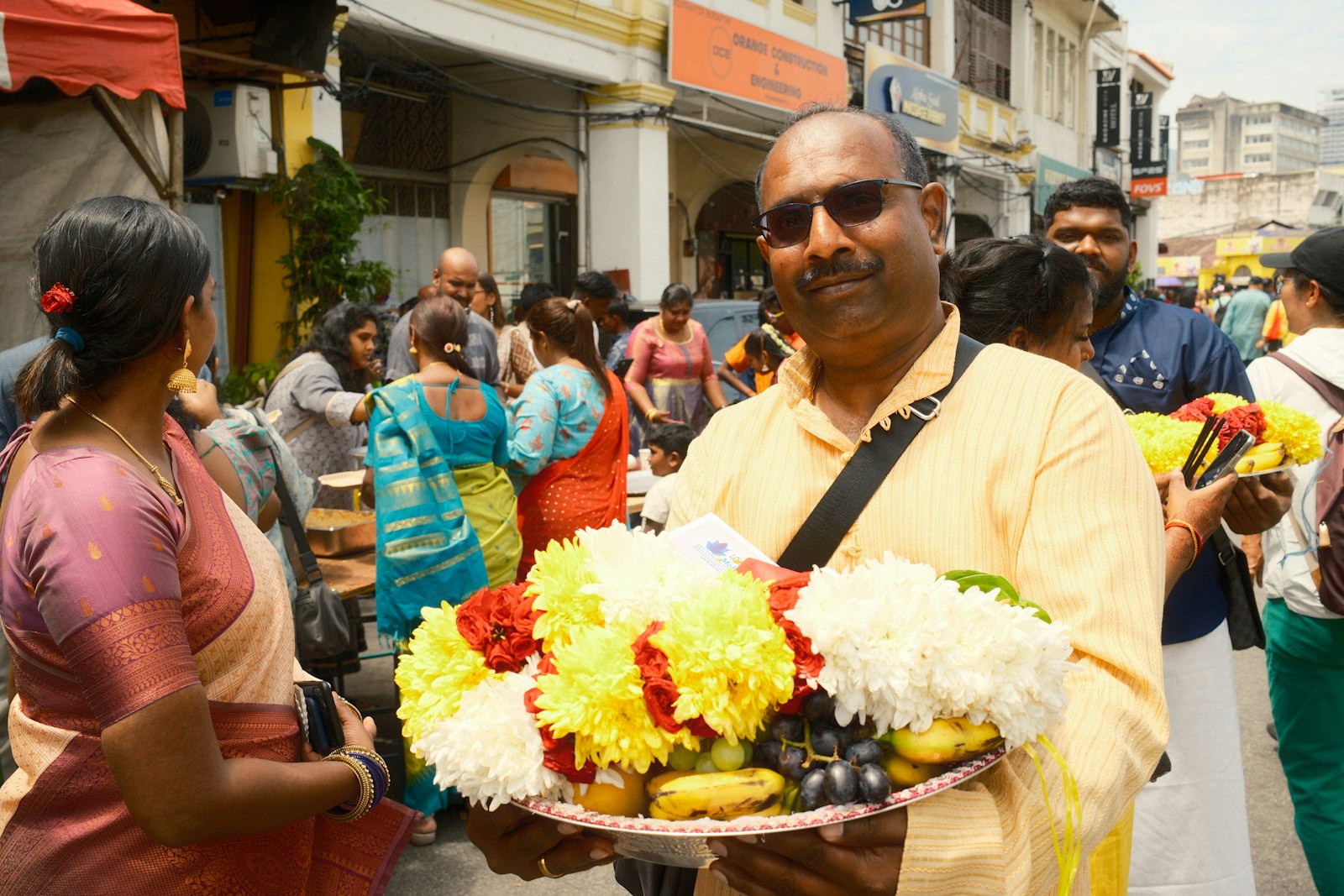 A man holding a plate of flowers in a crowded street