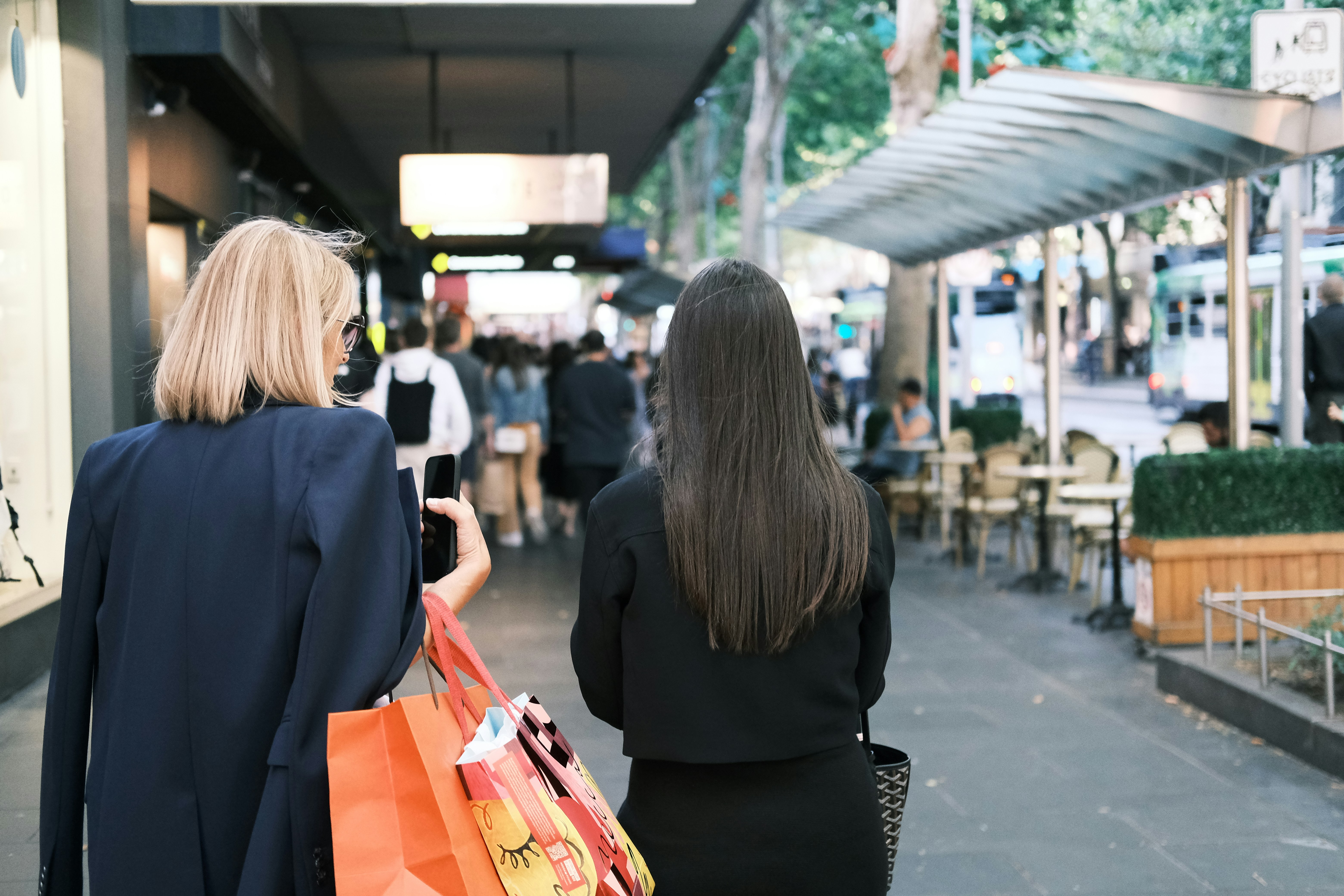 Two women walking down a street carrying shopping bags