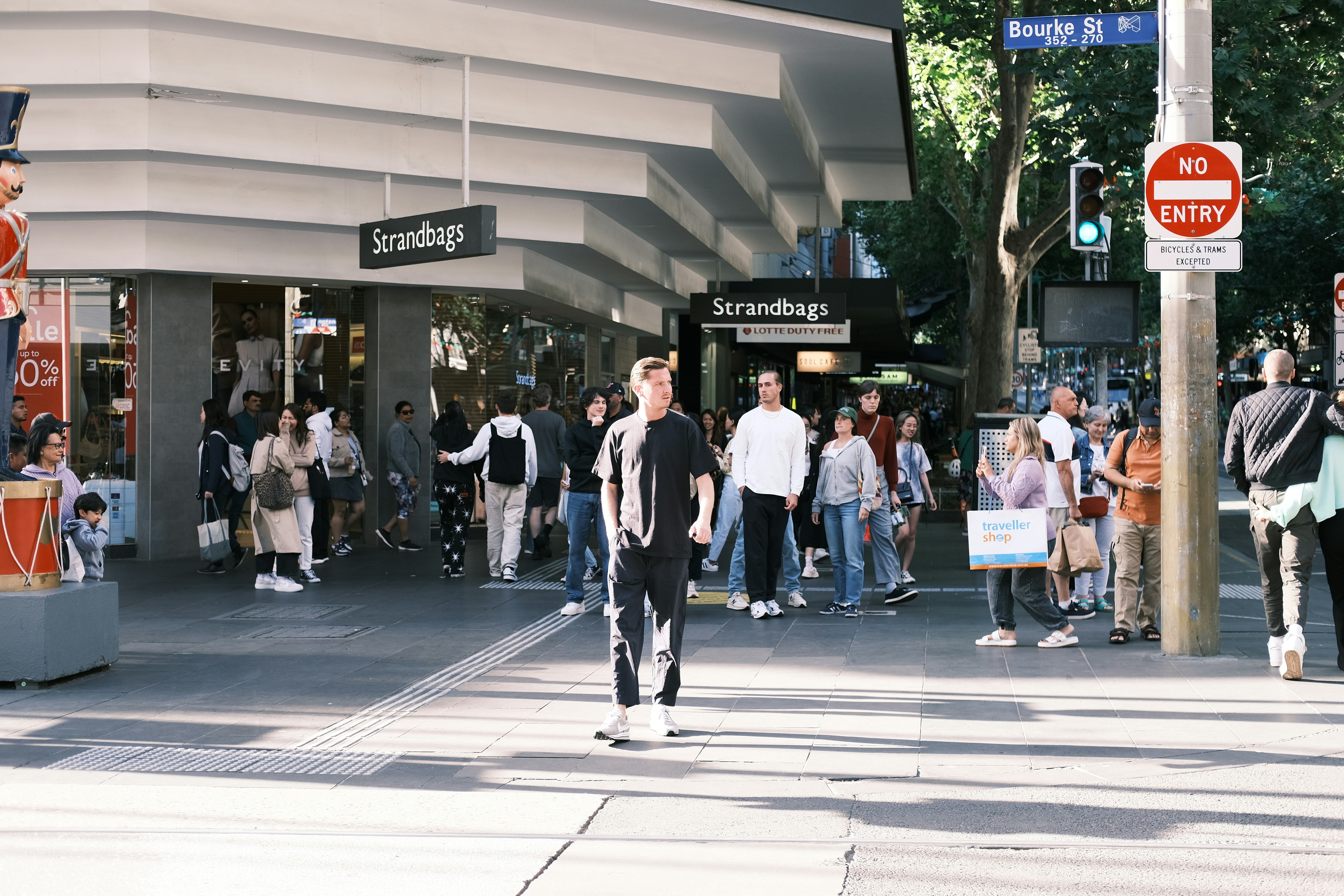 A man riding a skateboard down a street next to a crowd of people