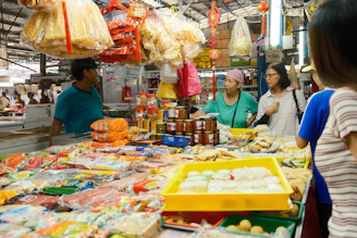 A group of people standing around a store filled with food