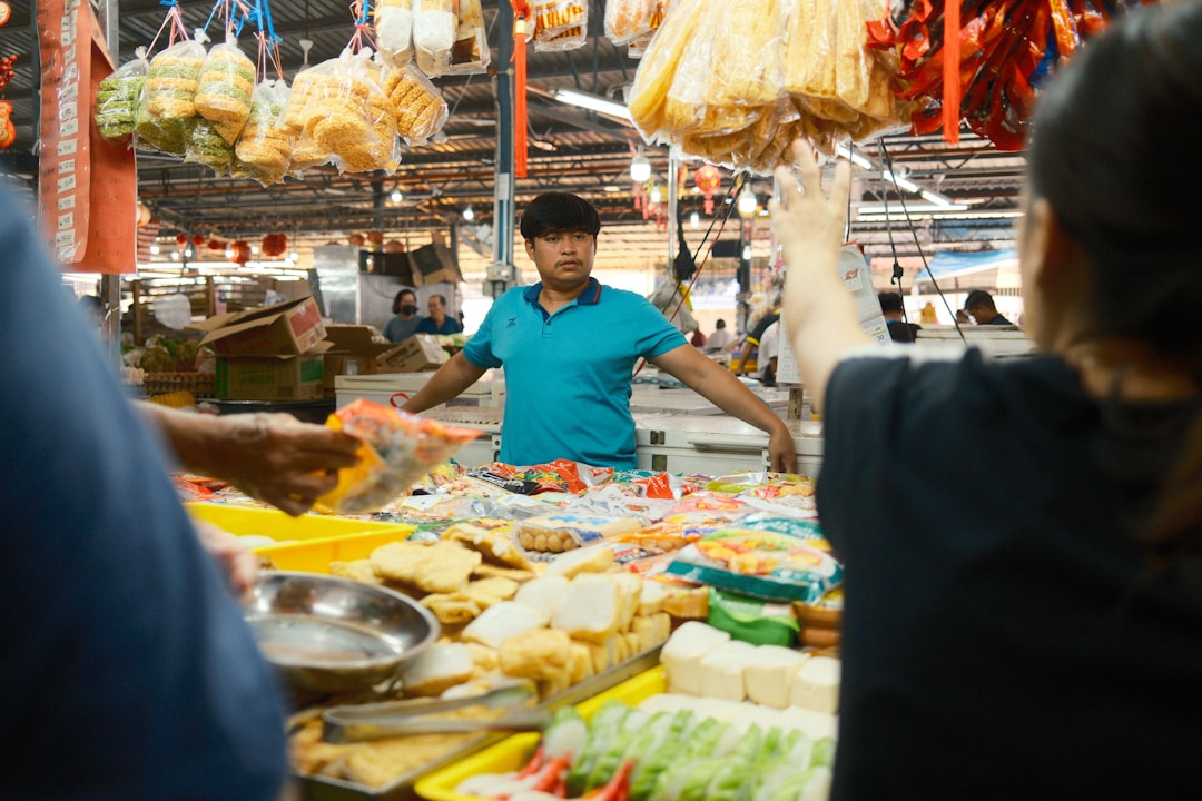 A bustling Chinese street food market in the morning with steaming food stalls and locals eating breakfast at outdoor tables