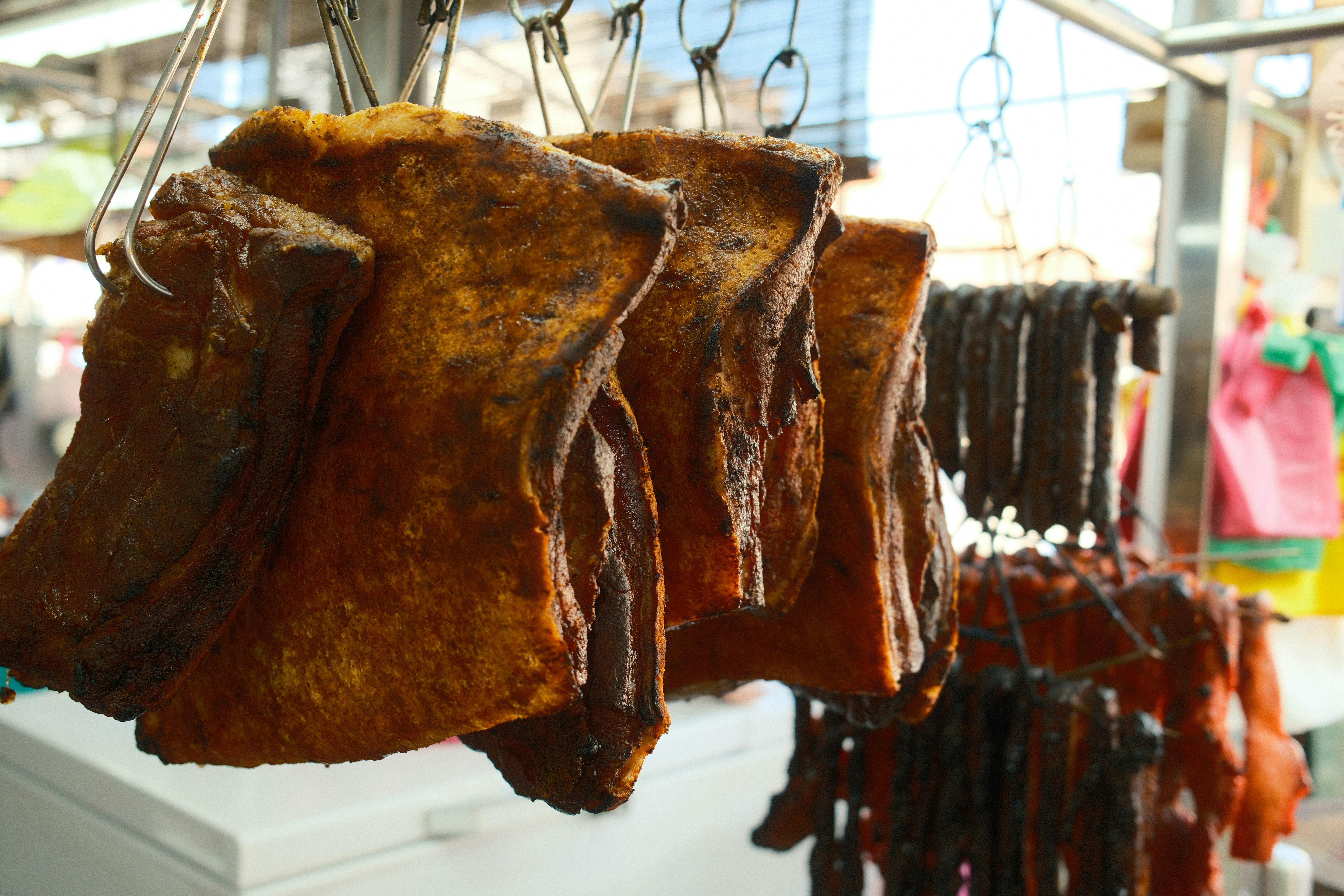 Varios trozos de carne colgados de ganchos en un mercado