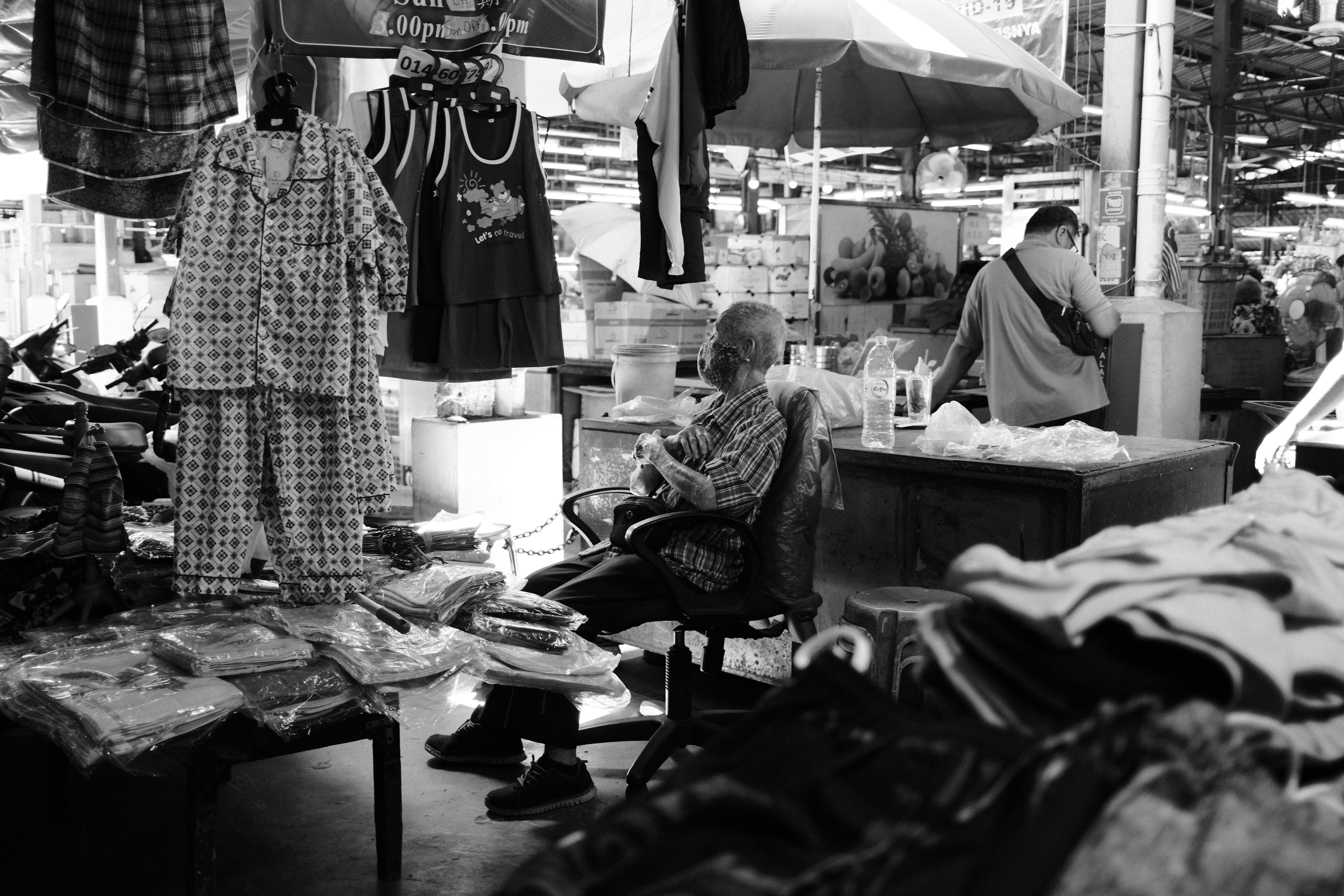 A black and white photo of a man sitting in a shop, 