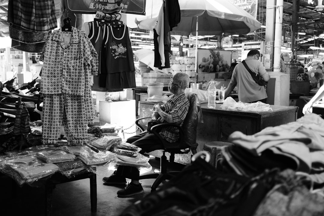A black and white photo of a man sitting in a shop,
