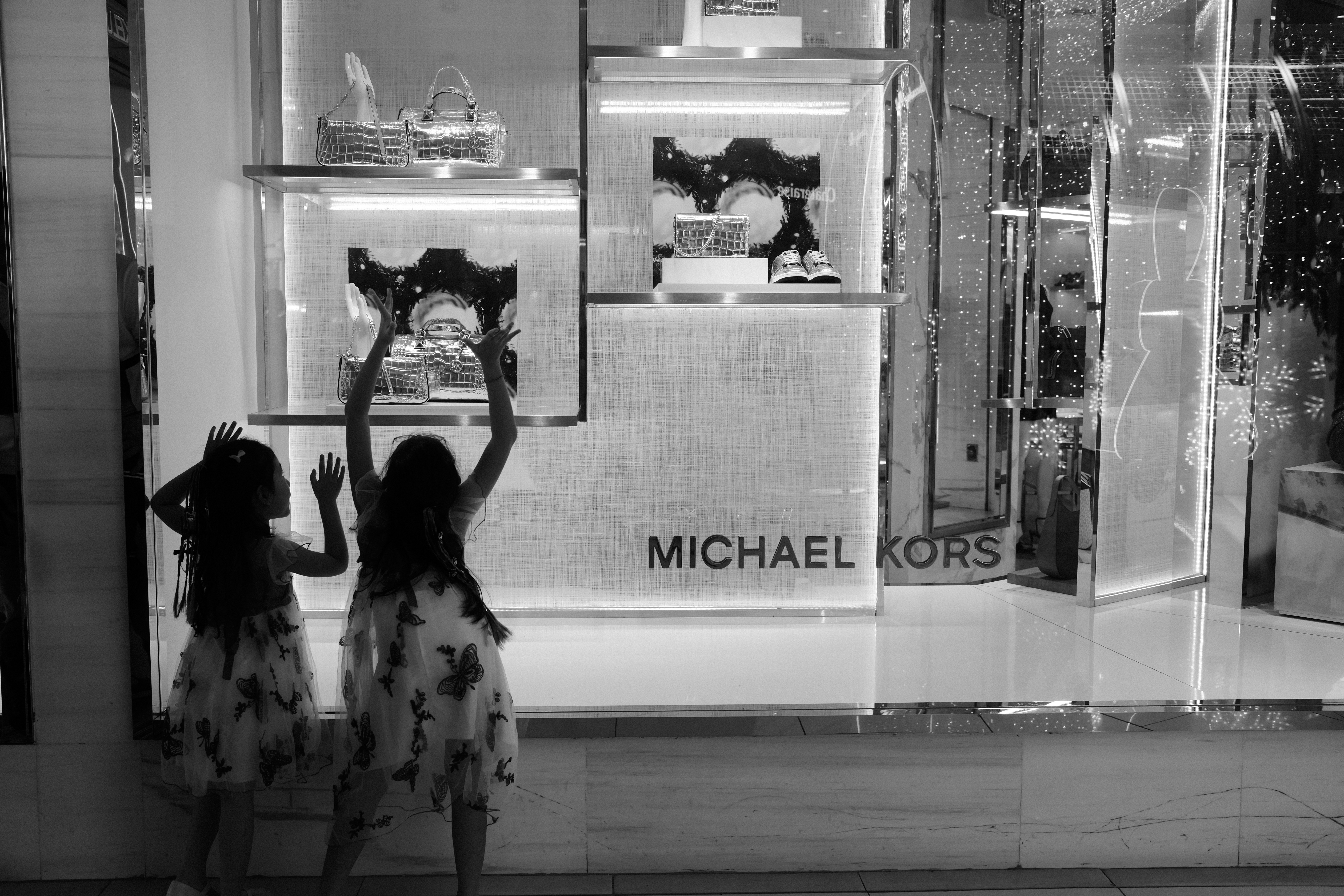 Two women standing in front of a store window