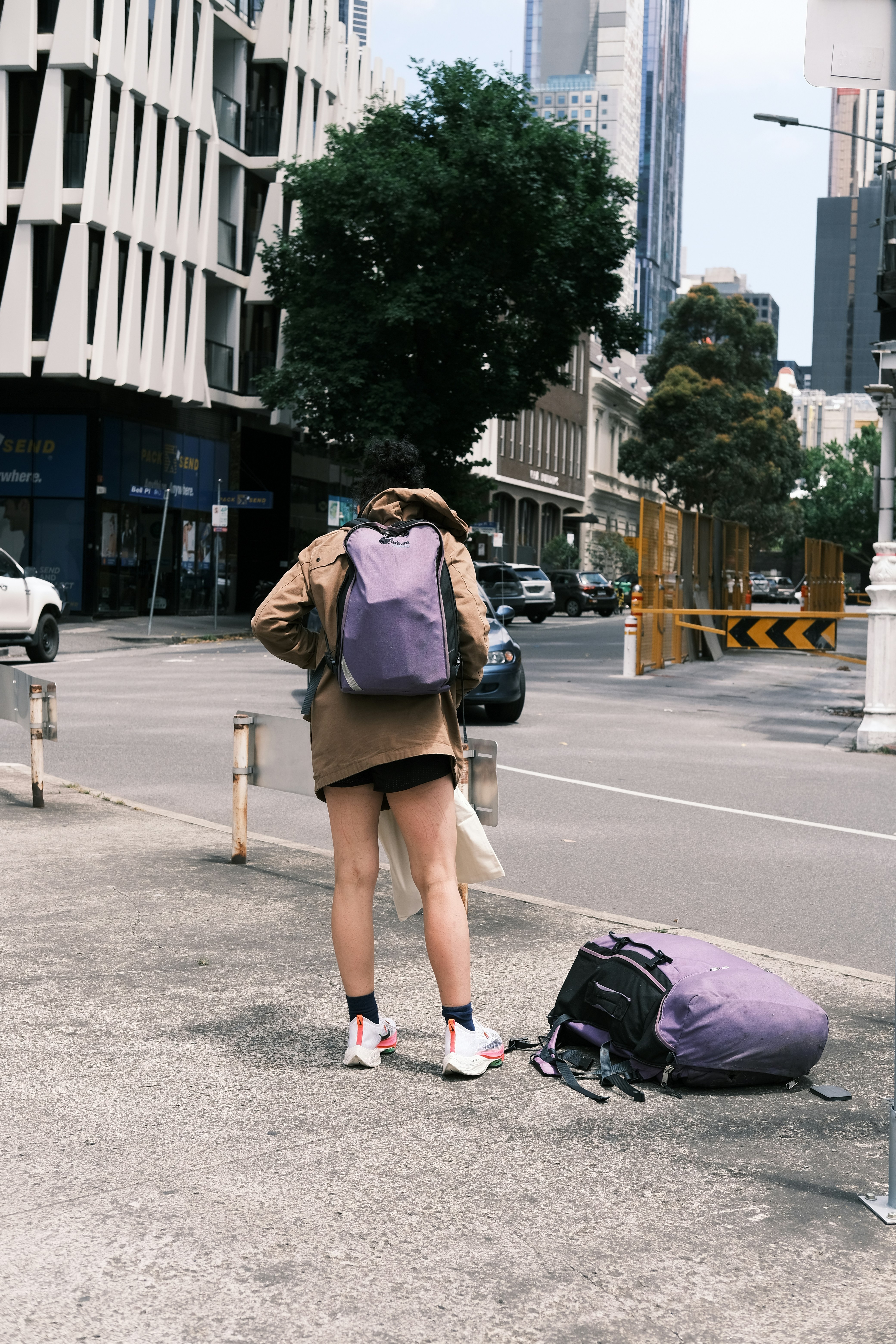 A woman with a backpack and a suitcase on the side of the road