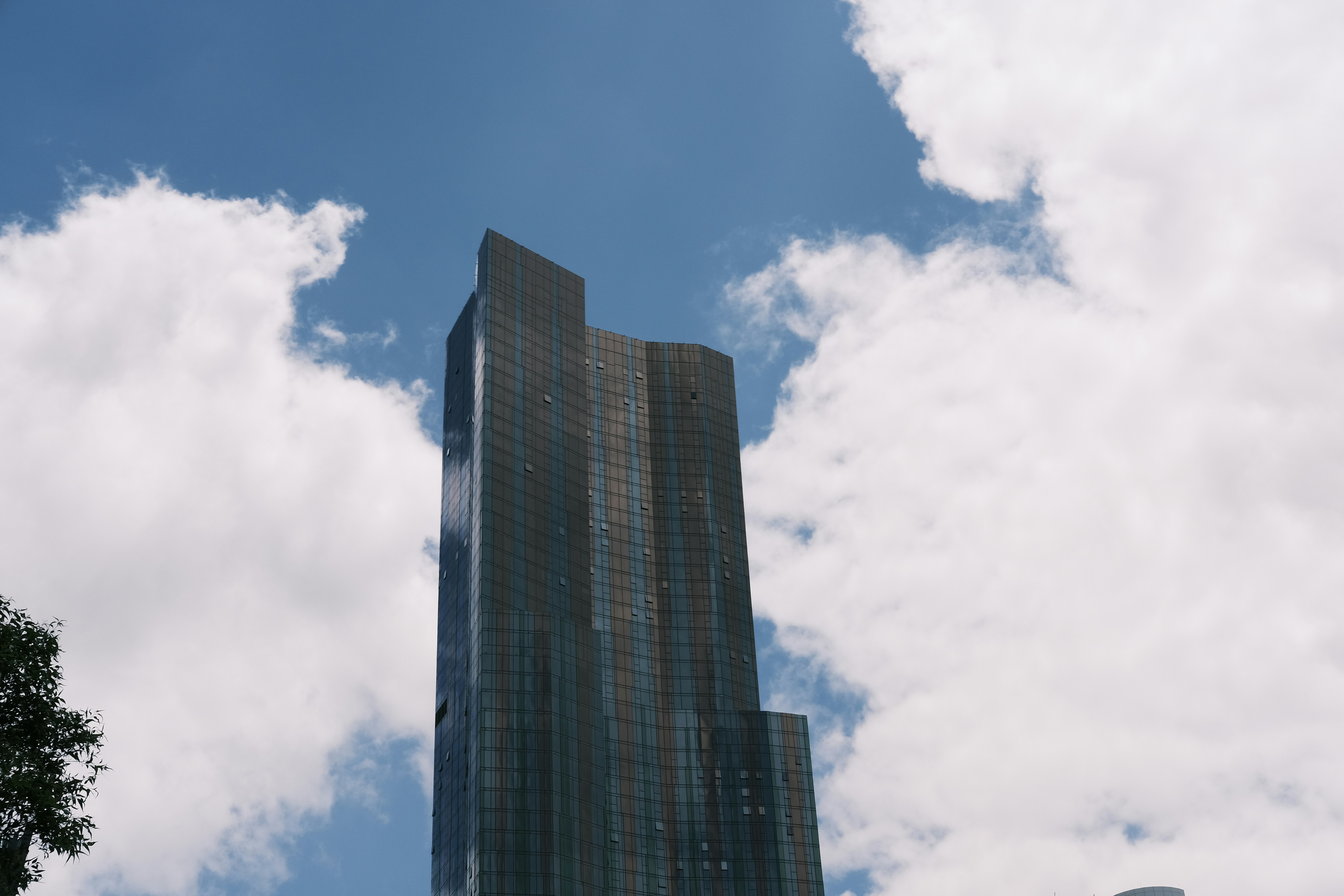 A very tall building sitting under a cloudy blue sky photo – Free City ...