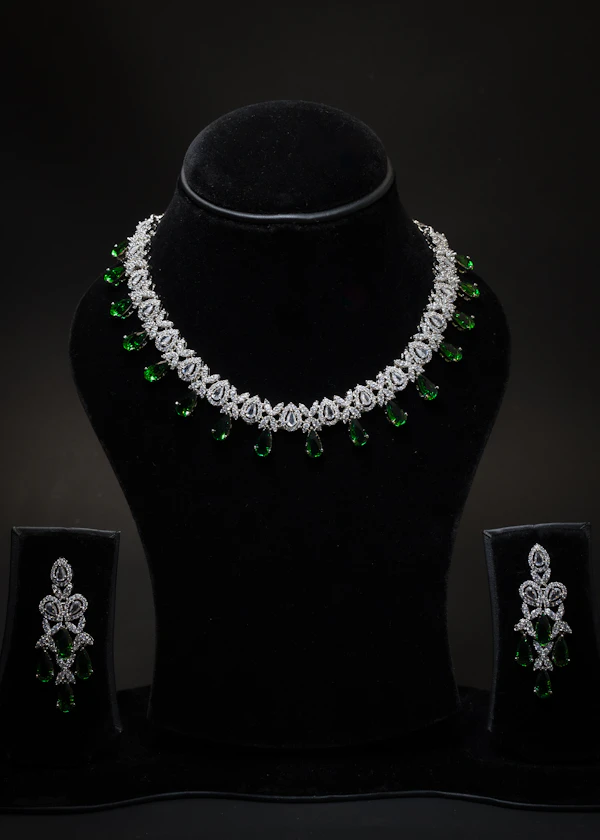 Silver crystal collar necklace with green stones and matching earrings on a display bust