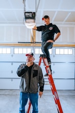 A man standing on a ladder next to another man
