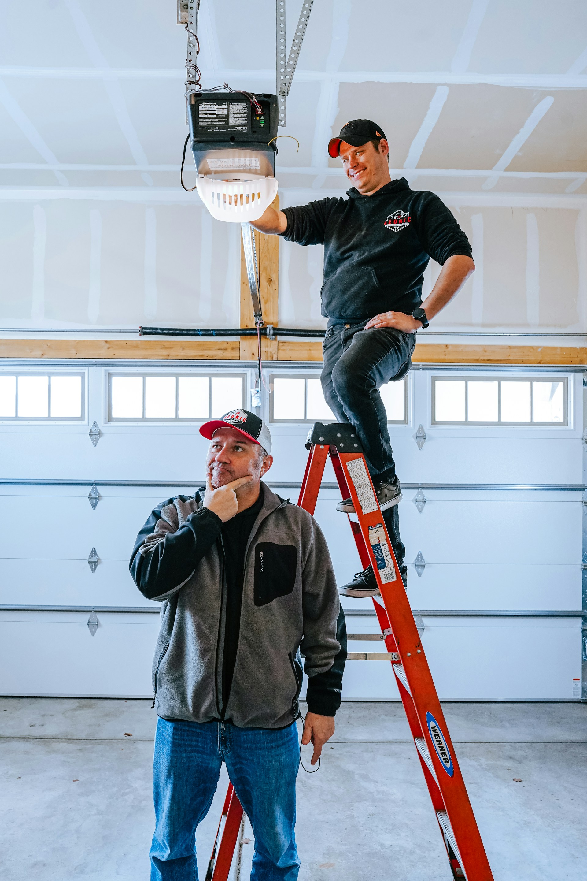 A man standing on a ladder next to another man