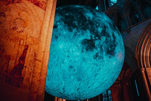 A large blue ball hanging from the side of a building