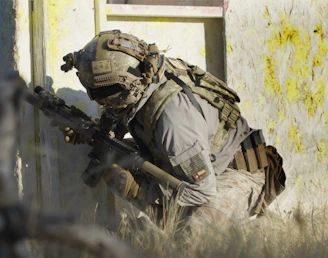 A soldier crouching down with a rifle in his hand