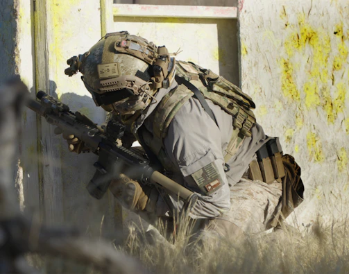 A soldier crouching down with a rifle in his hand