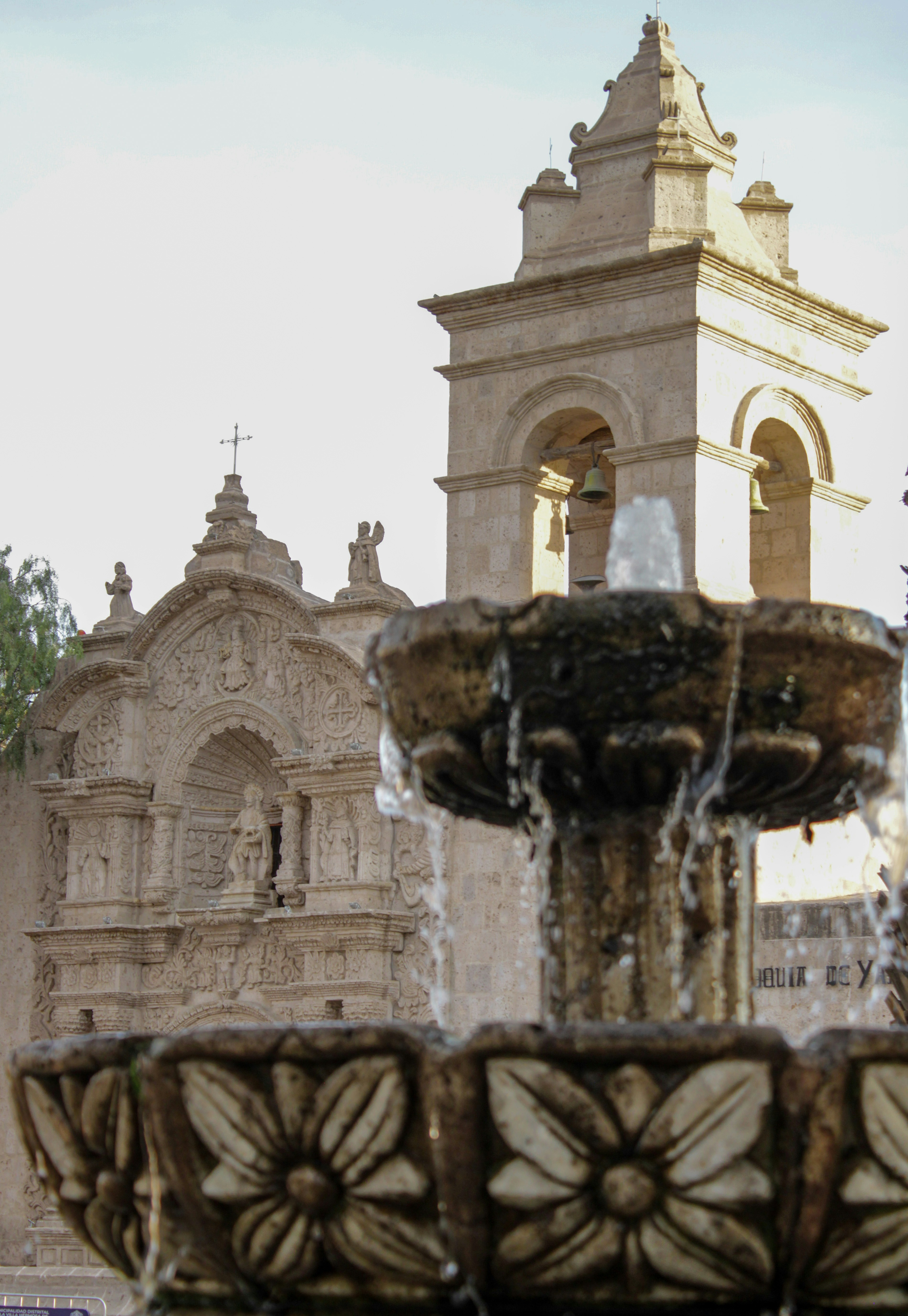 A fountain with a clock tower in the background