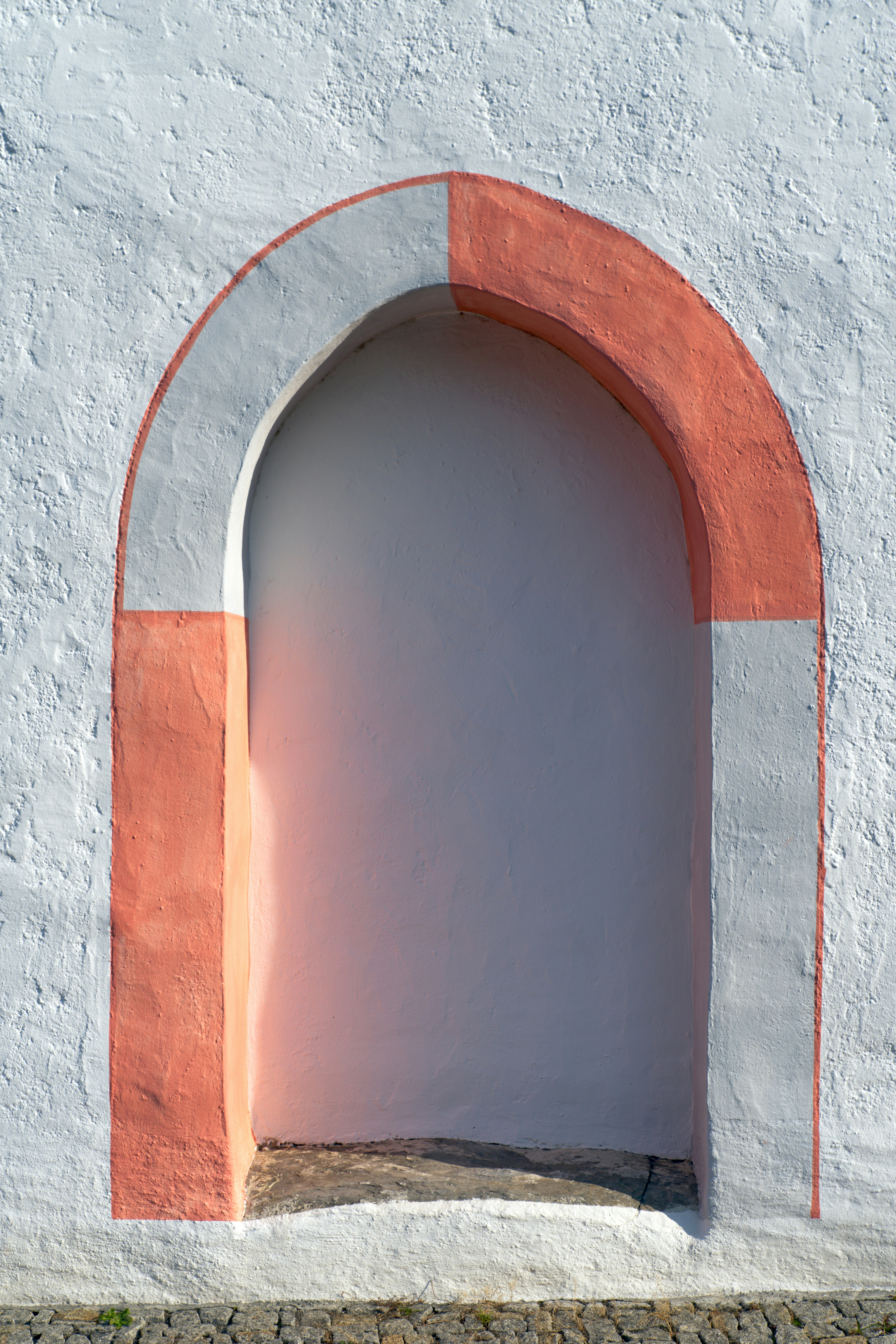 A white wall with a red arch on it