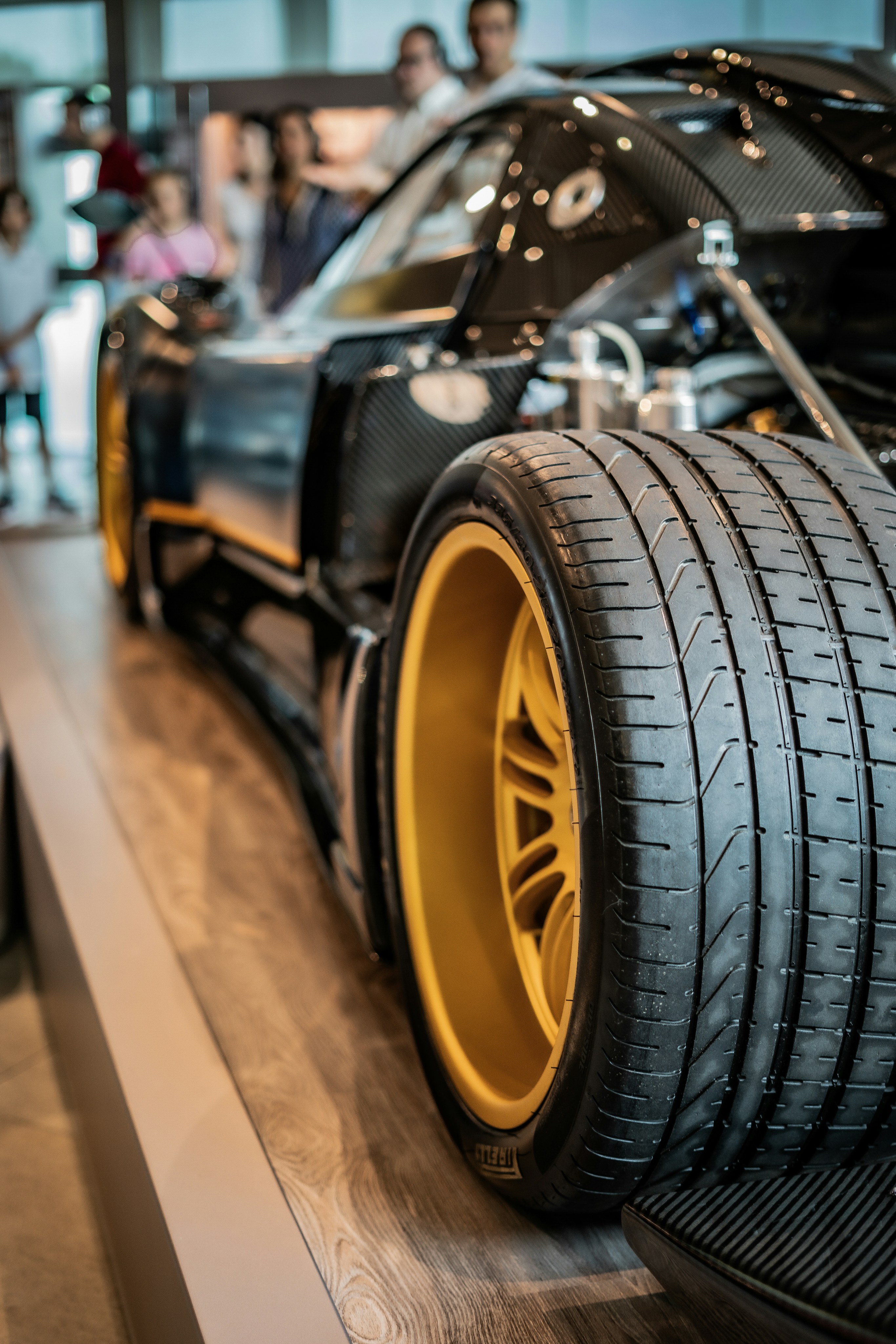 A black car with yellow rims on display at a car show