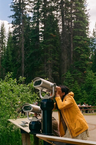 A woman looking through a telescope at a forest