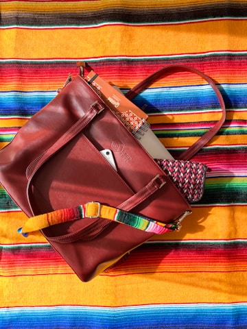 A red purse sitting on top of a colorful blanket