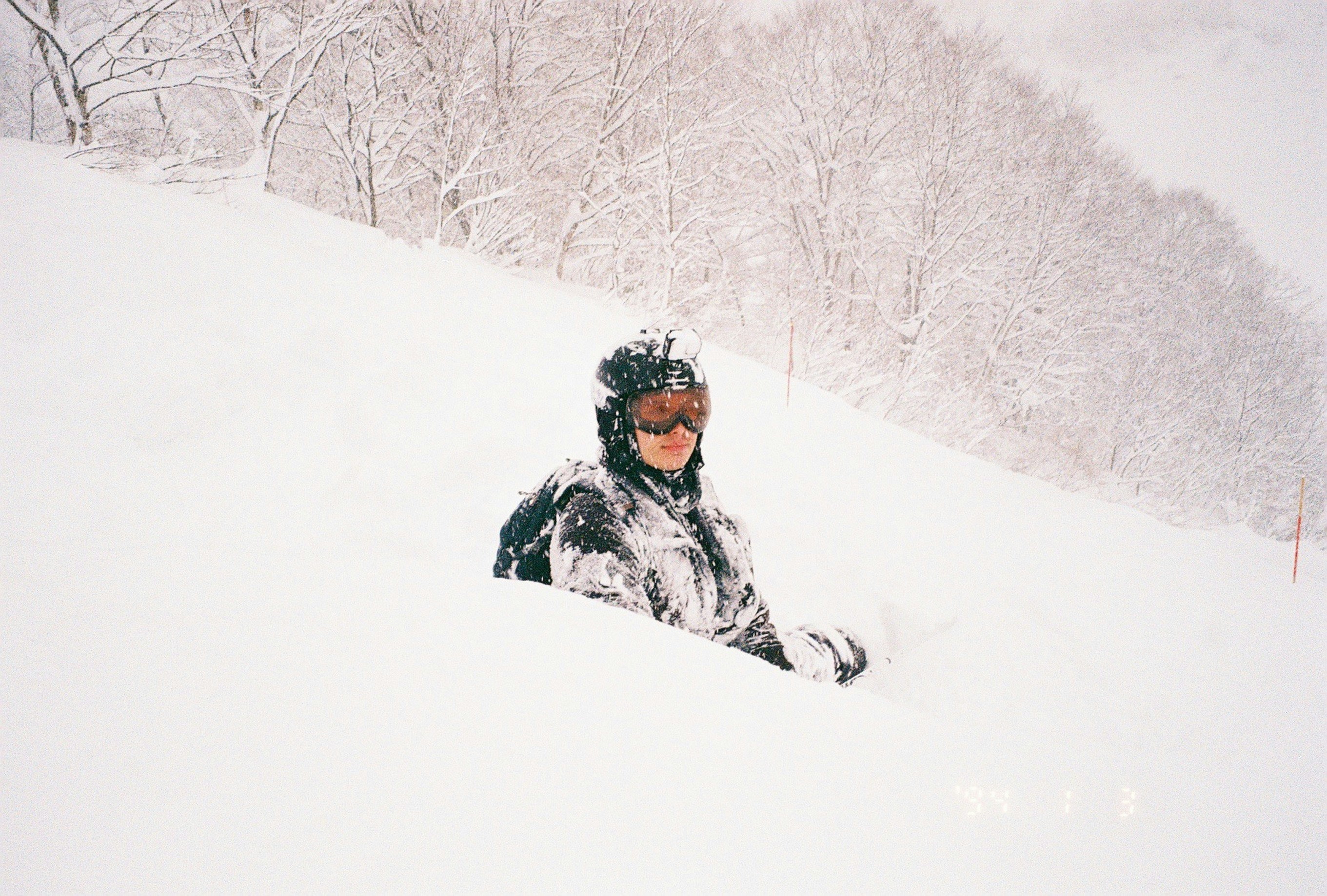Child laughing while sledding down a gentle snowy hill, parent watching