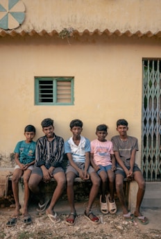 A group of men sitting on a bench in front of a building
