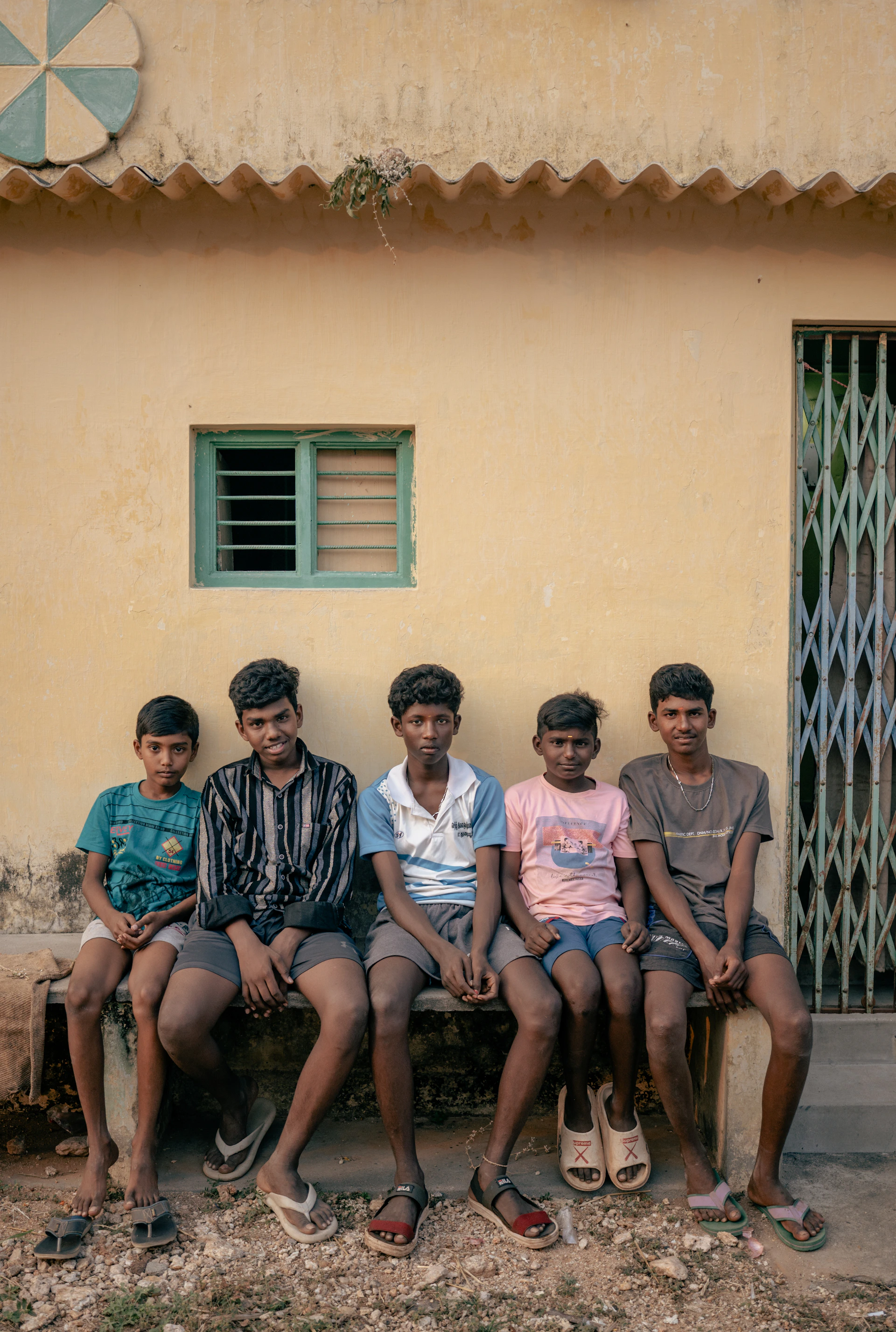 A group of men sitting on a bench in front of a building