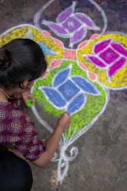A woman is drawing a flower on the ground