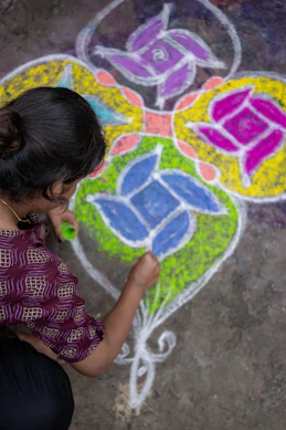 A woman is drawing a flower on the ground