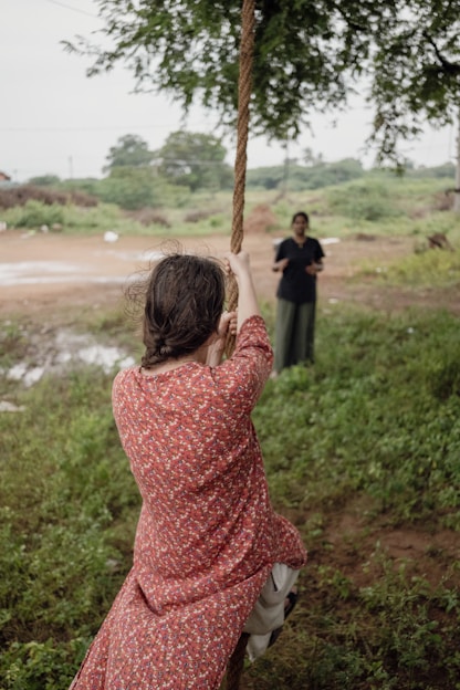 A woman in a red dress swinging on a rope