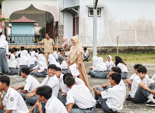 A group of people sitting on the ground in front of a building