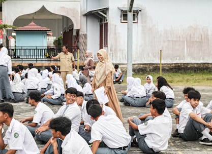 A group of people sitting on the ground in front of a building