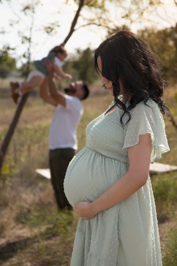 A pregnant woman standing in a field next to a man