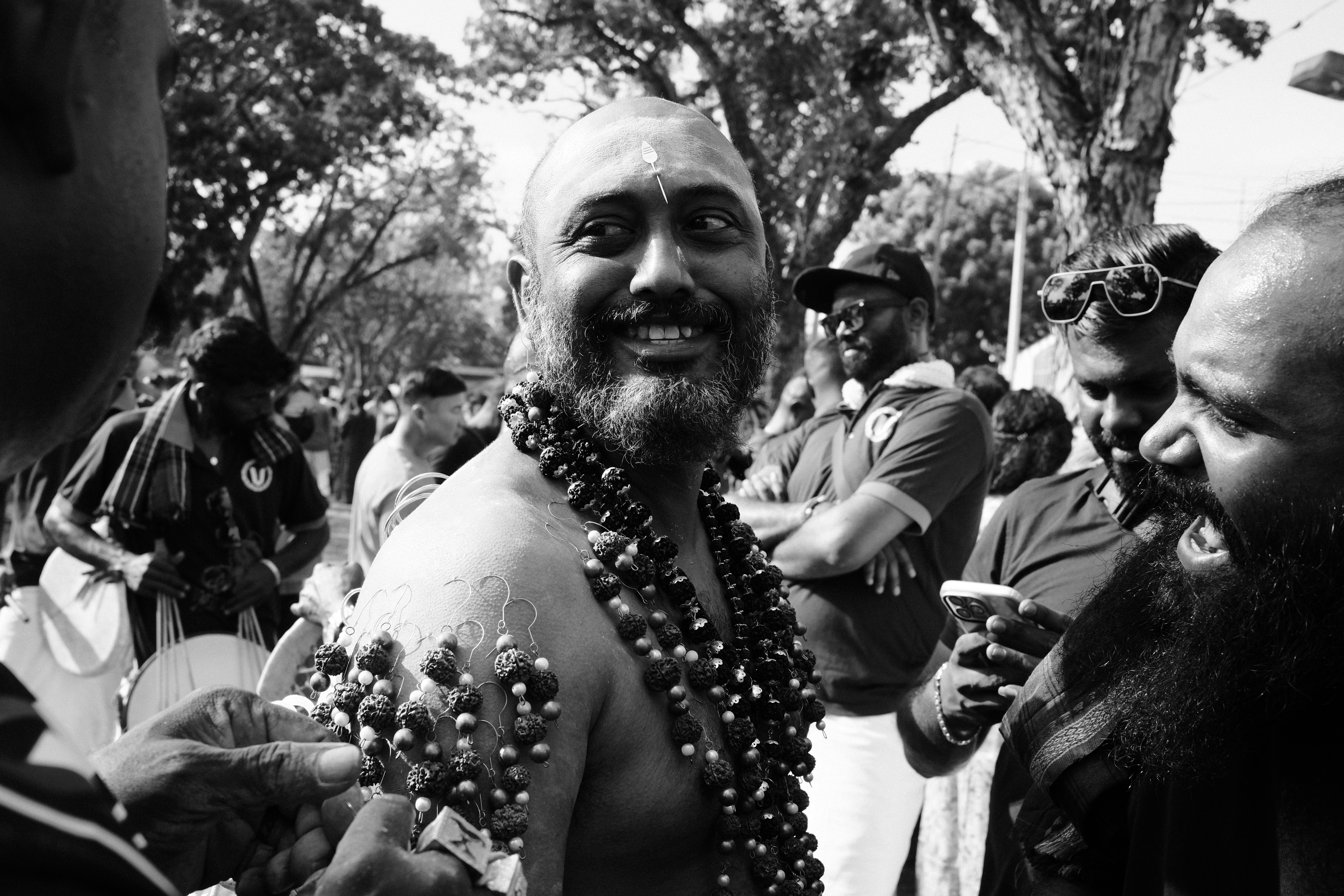 Manickam Tagore, a middle-aged man in a white shirt, smiling and greeting party workers at a bustling political rally in Tamil Nadu.