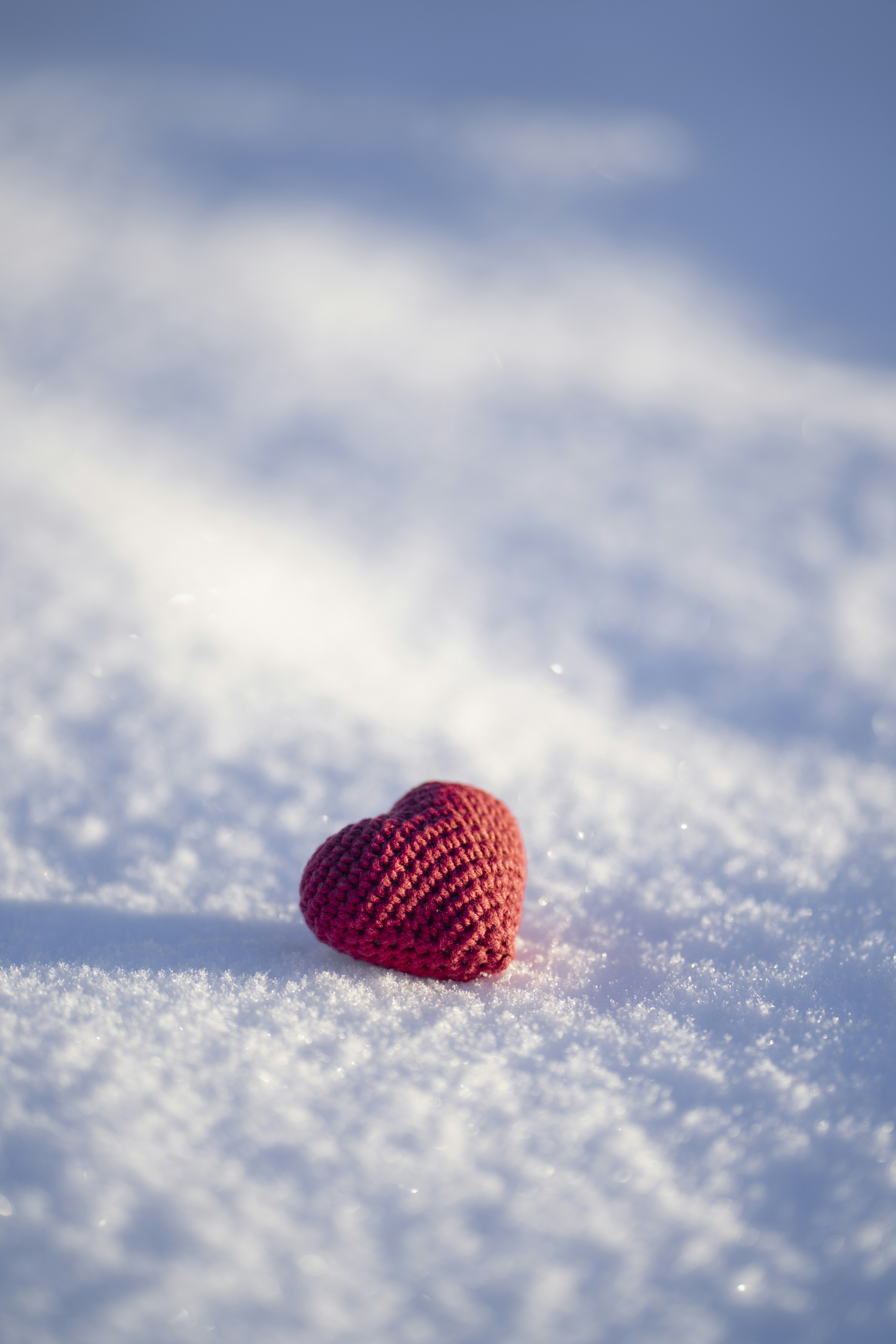 A red crocheted heart sitting in the snow