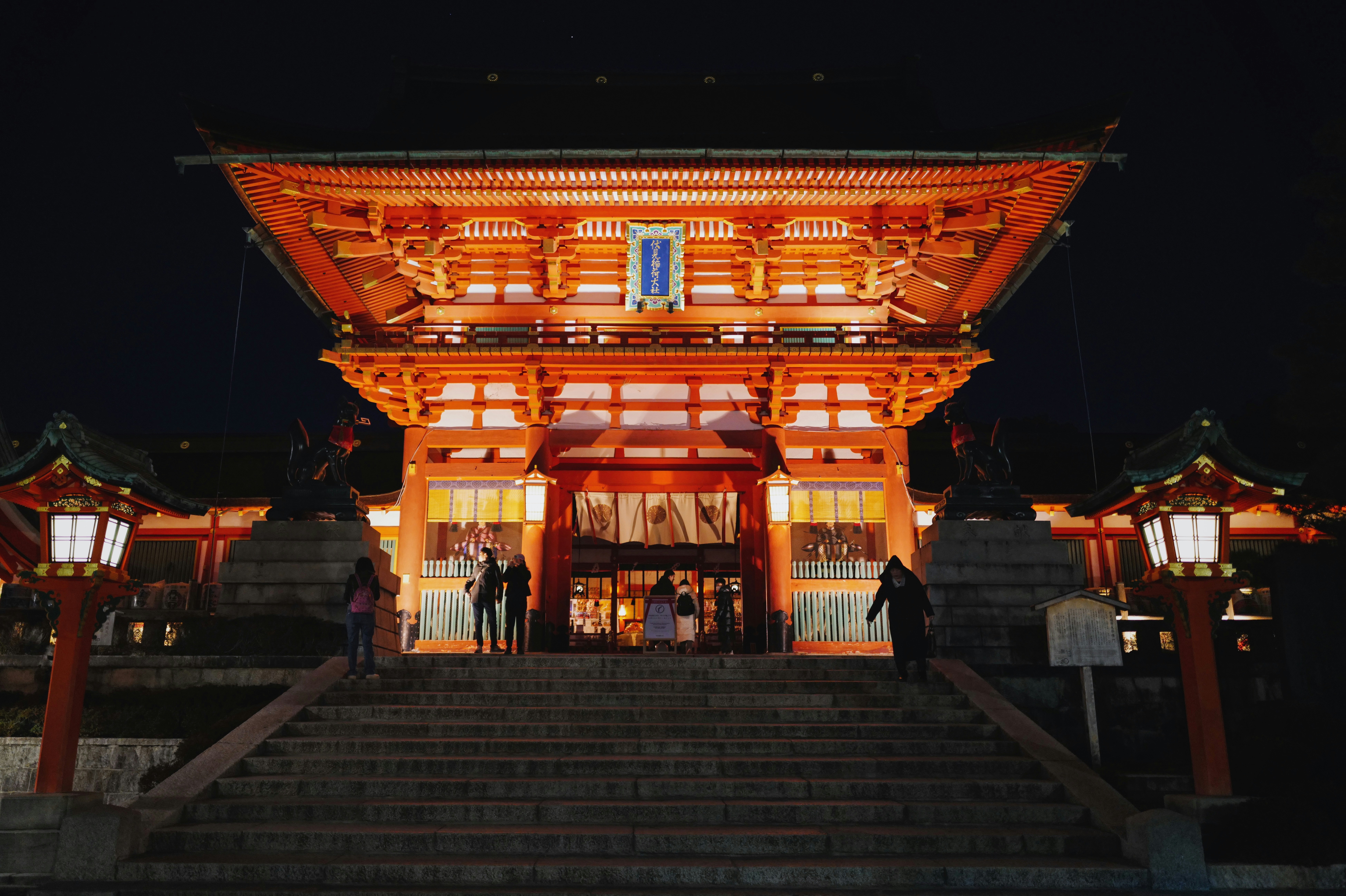 Illuminated entrance gate of a traditional Kyoto temple at night, capturing the city's historic atmosphere for travelers planning their stay